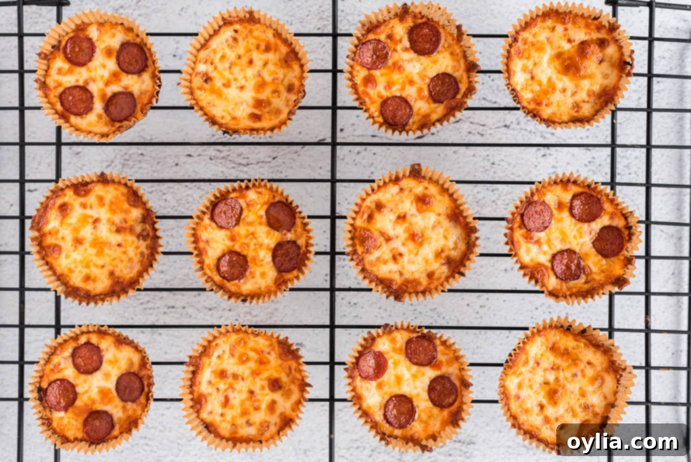 Baked cauliflower pizza bites with melted cheese and pepperoni, cooling on a rack after coming out of the oven.
