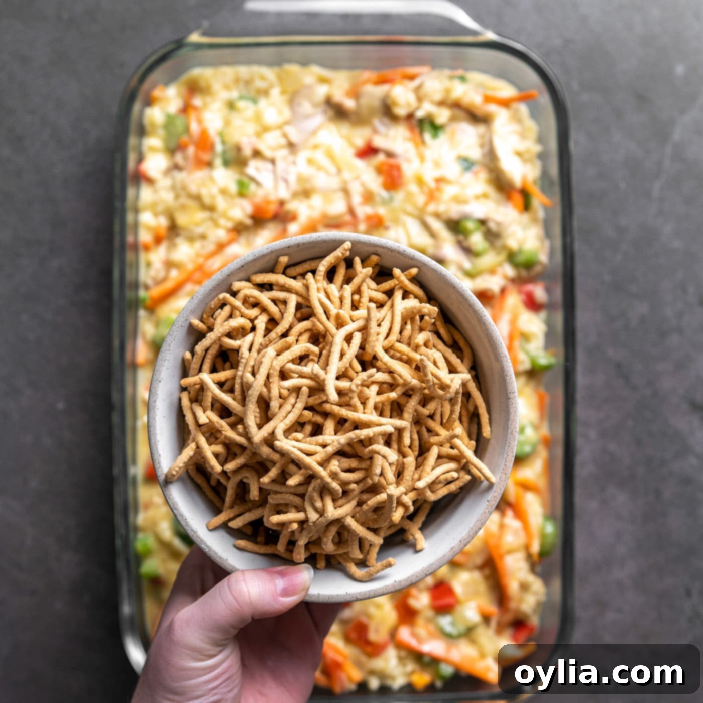 Chow mein noodles generously spread over the chicken and rice casserole mixture in the baking dish.