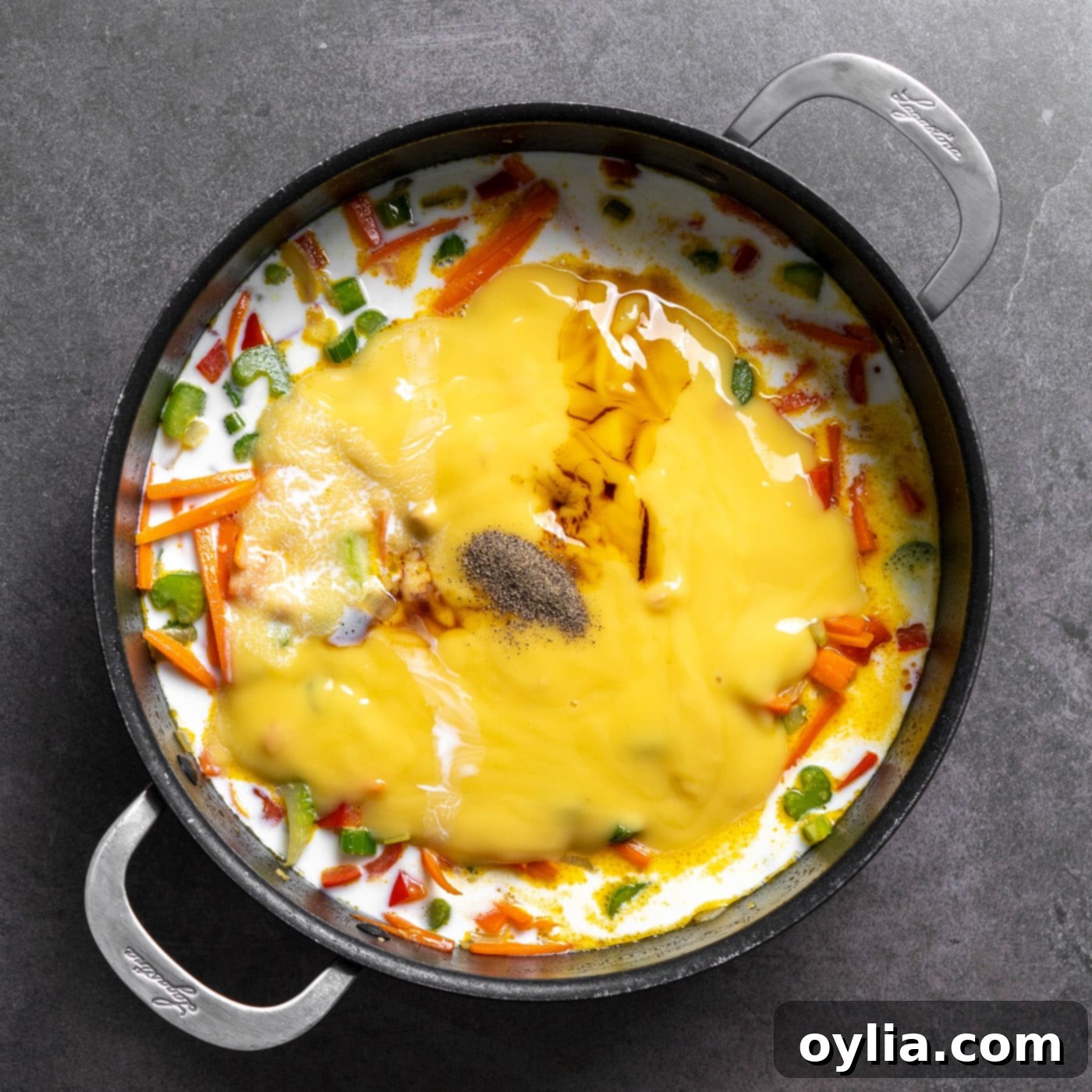Condensed cream of chicken soup, milk, soy sauce, and black pepper added to the sautéed vegetables in the pan.