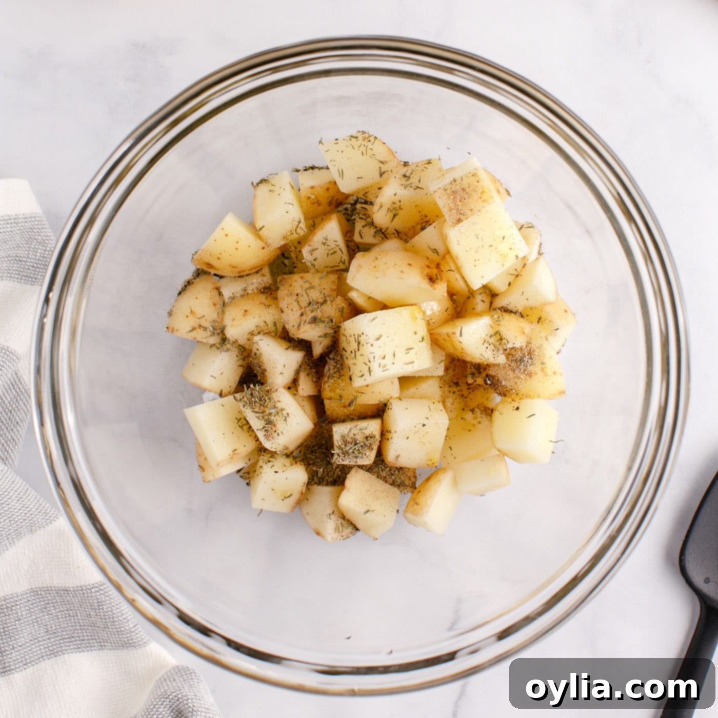 cubed potatoes in a bowl with seasonings and oil