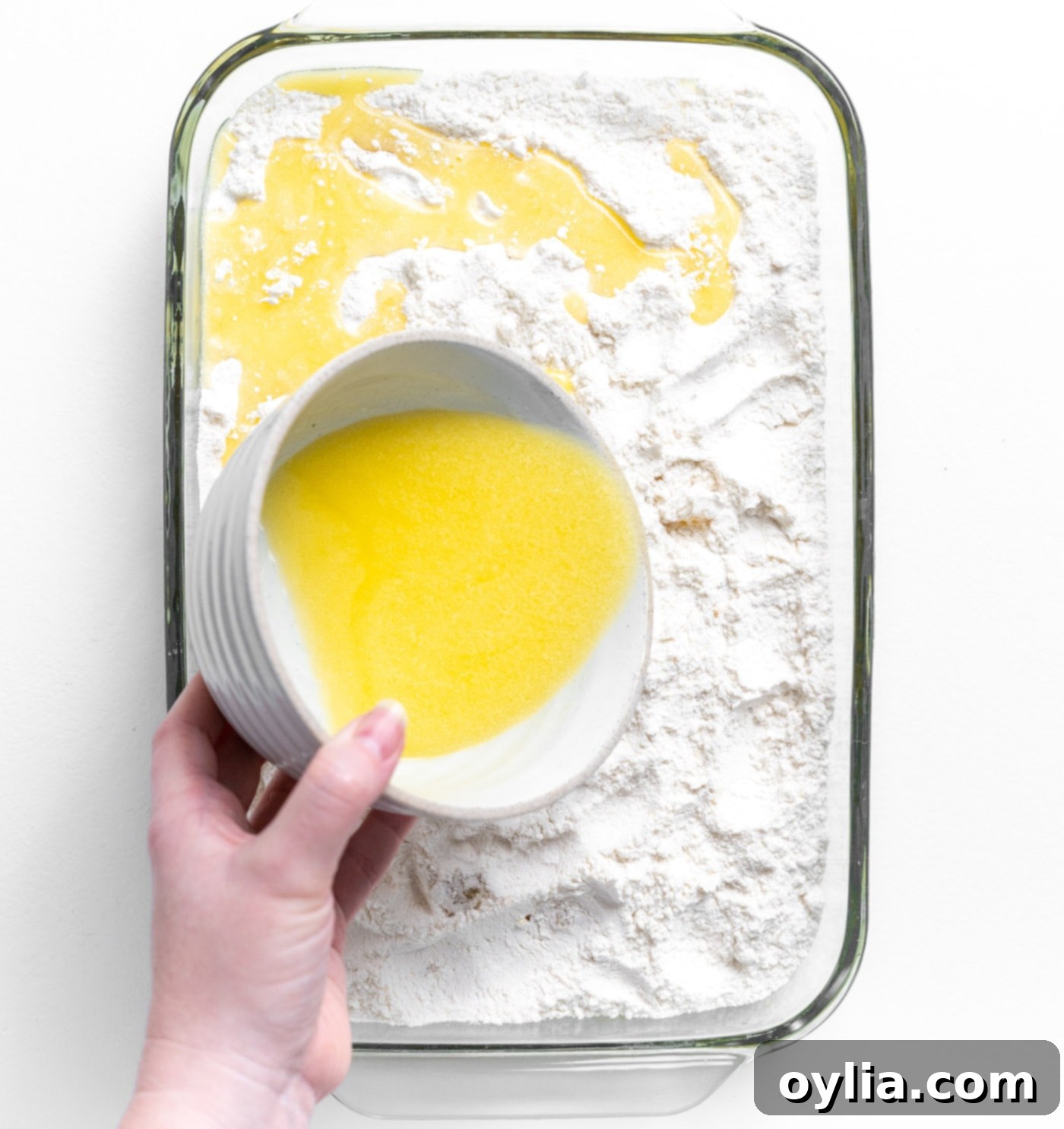 Melted butter being poured evenly over the dry cake mix layer in the dump cake