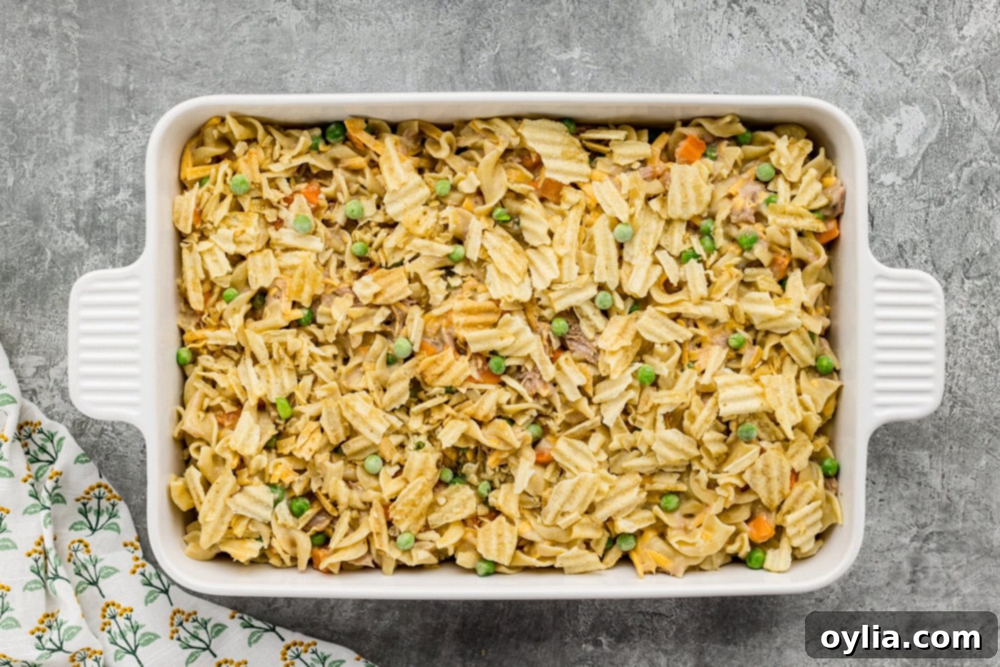 crushed potato chips sprinkled on top of tuna casserole in a baking dish