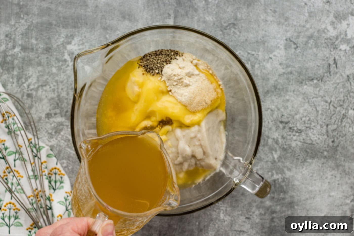 pouring chicken broth into mixing bowl of seasonings and cream of chicken and mushroom soup