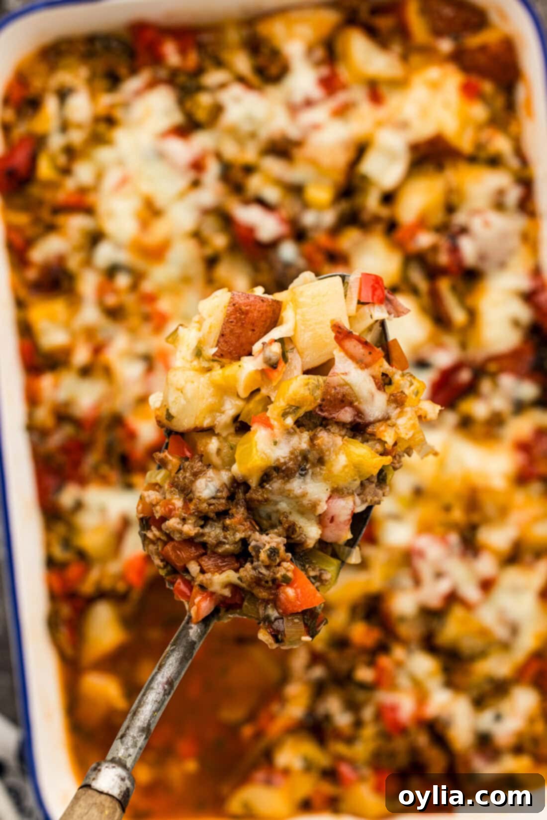 Hearty Sausage and Spud Bake 11 Spoonful of Sausage and Potato Casserole held above a casserole dish
