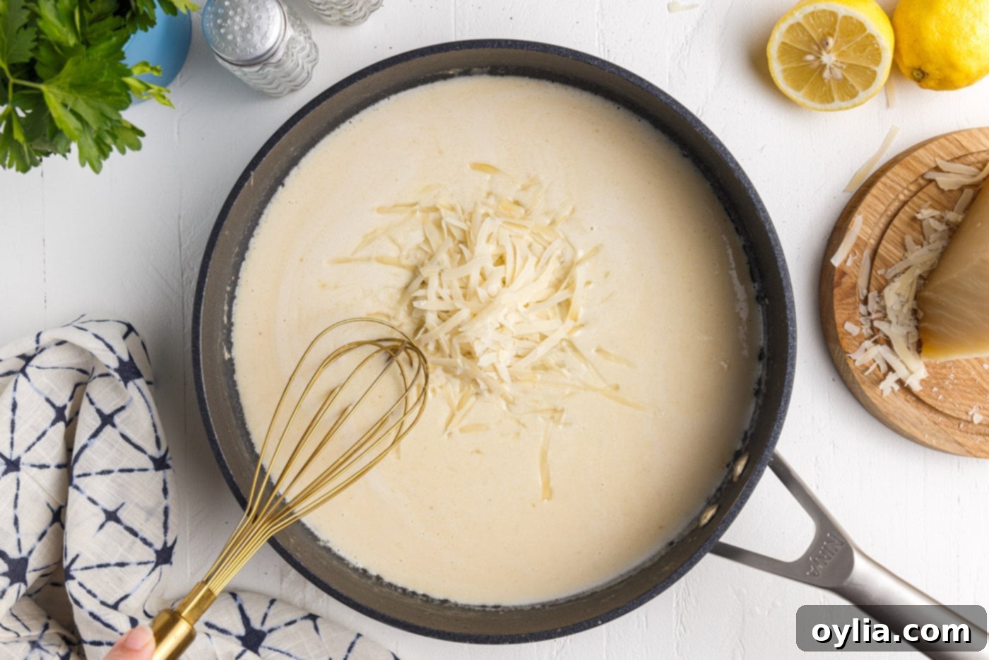 whisking parmesan cheese into creamy lemon garlic sauce