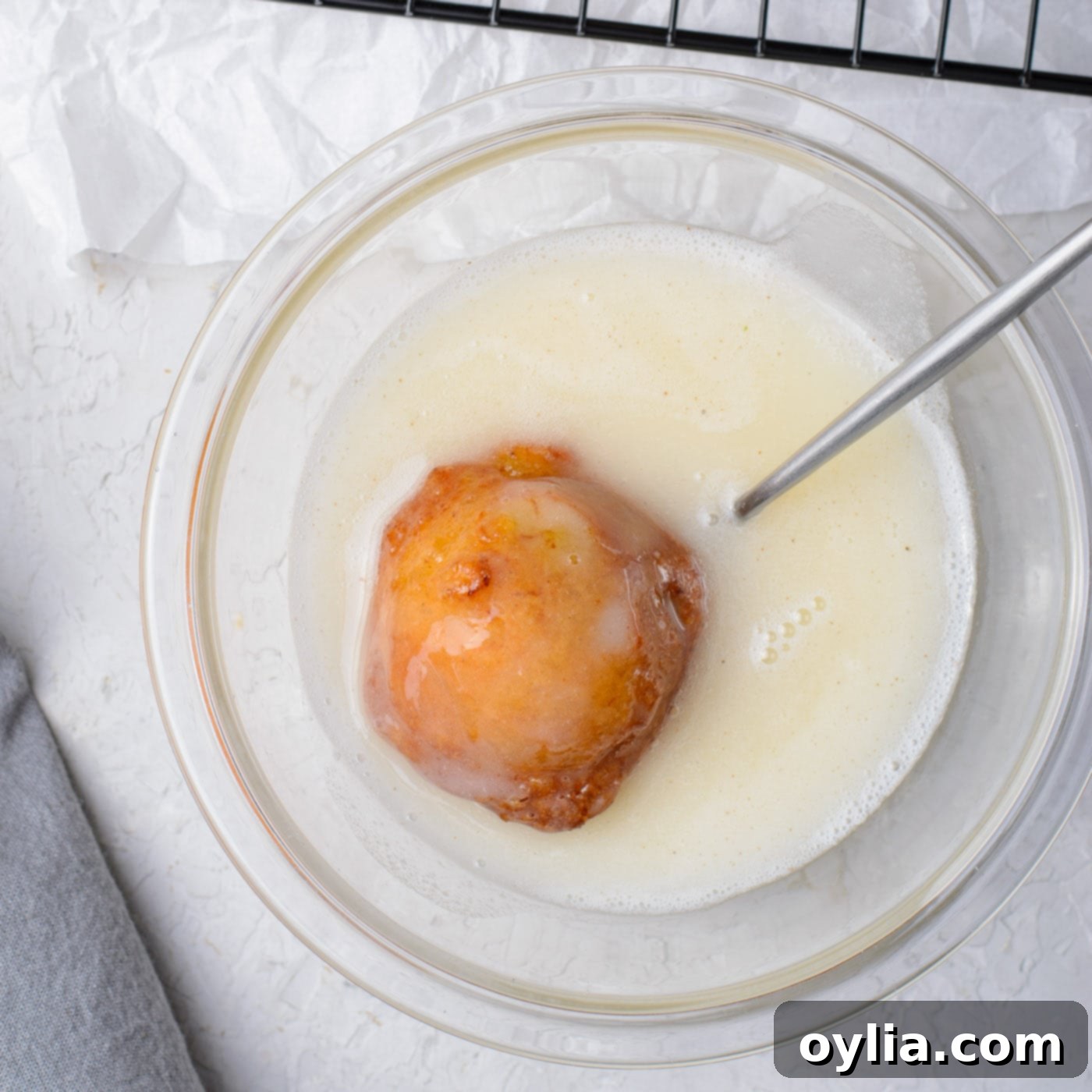 dunking banana fritter into sugar glaze