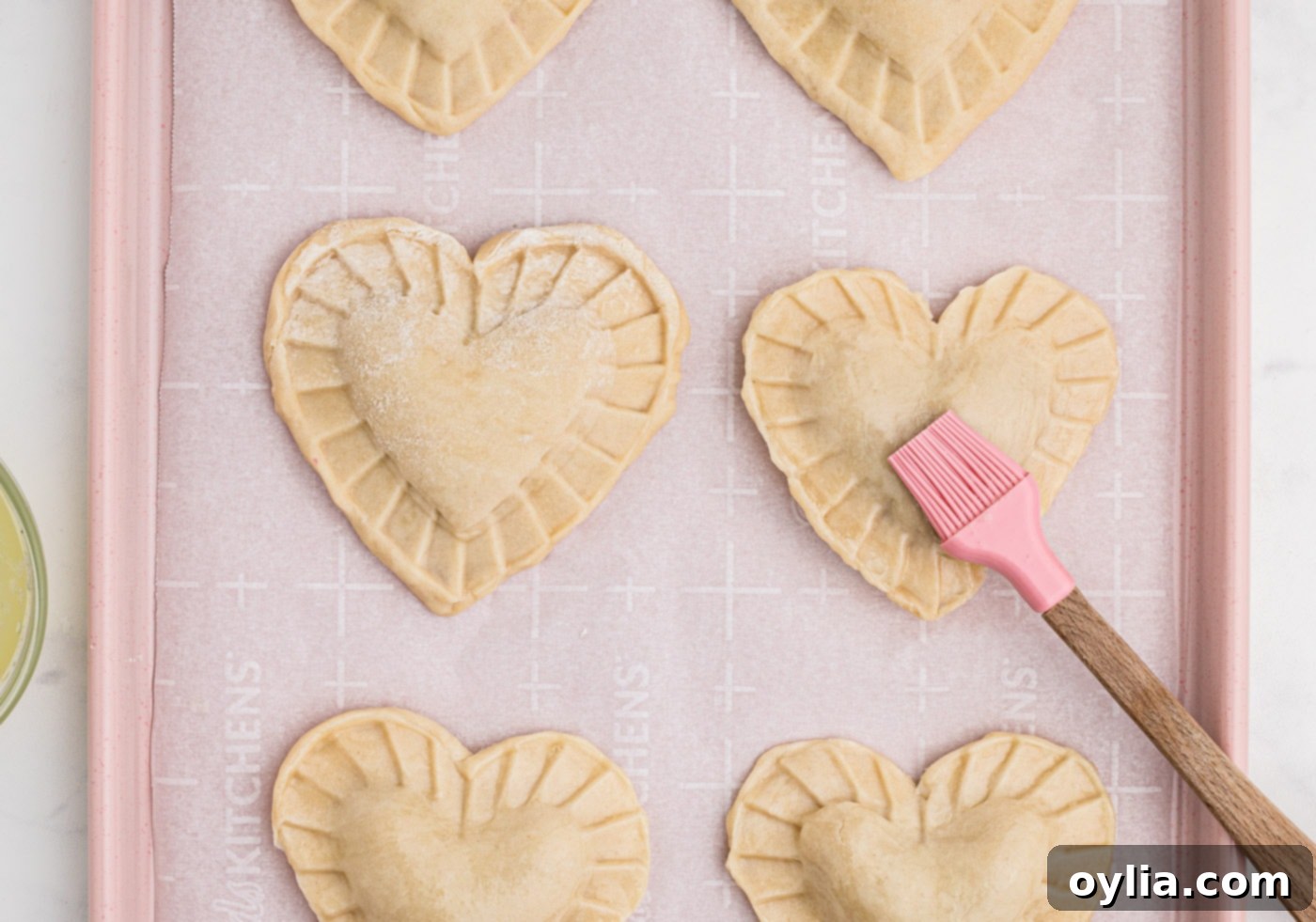 brushing egg wash over heart shaped cherry hand pies