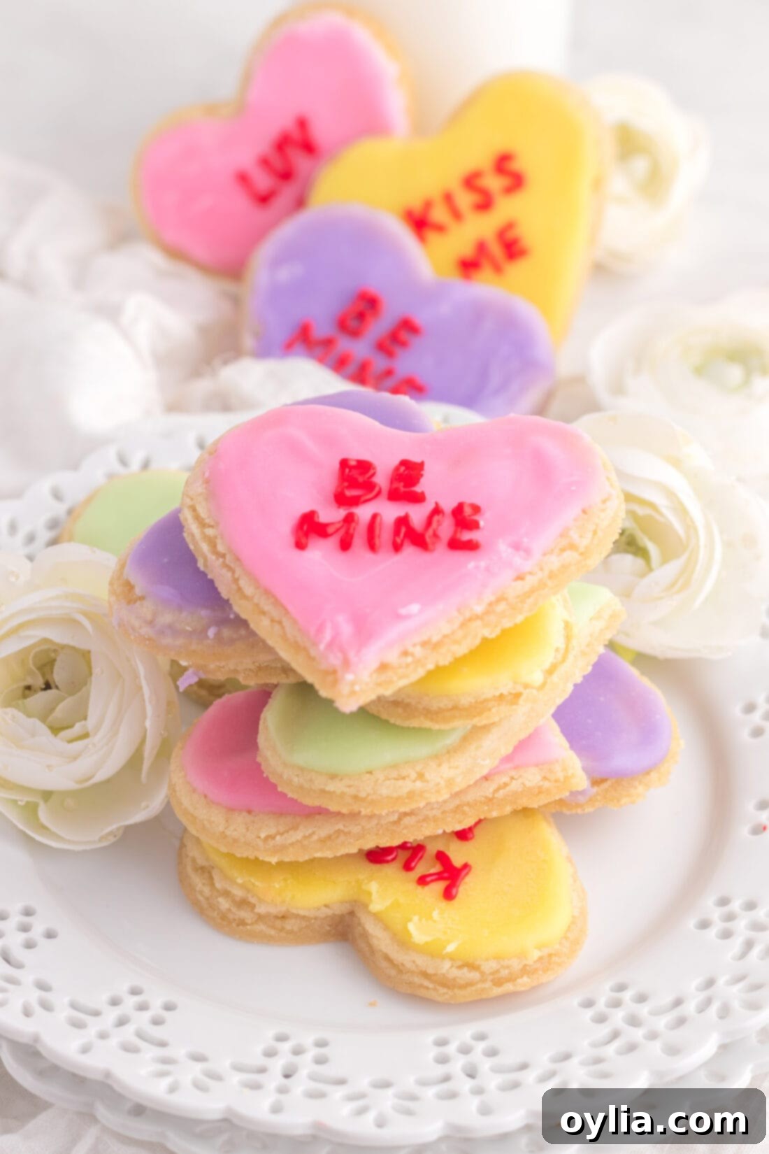 Sweet Talk Cookies 3 A stack of freshly decorated pastel conversation heart cookies, showcasing the smooth, professional finish achieved with the frosting hack.