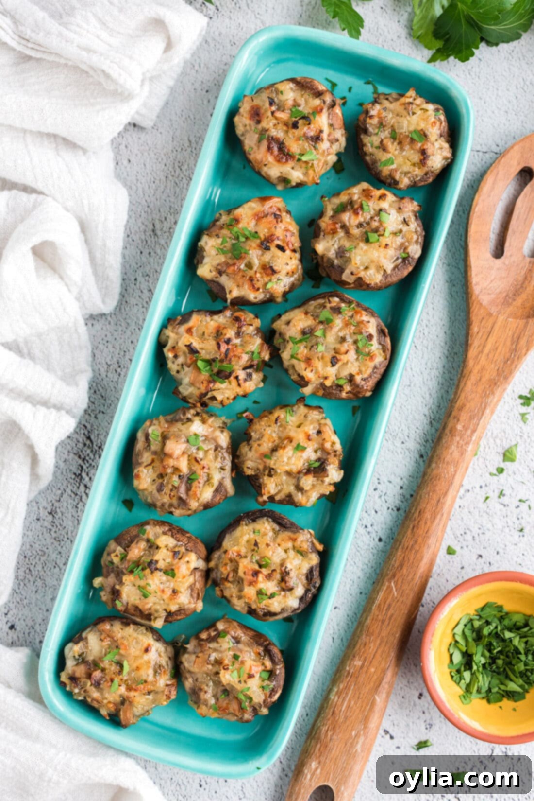 A vibrant platter of golden-brown cheesy stuffed mushrooms, garnished with fresh parsley, ready to be served as an appetizer.