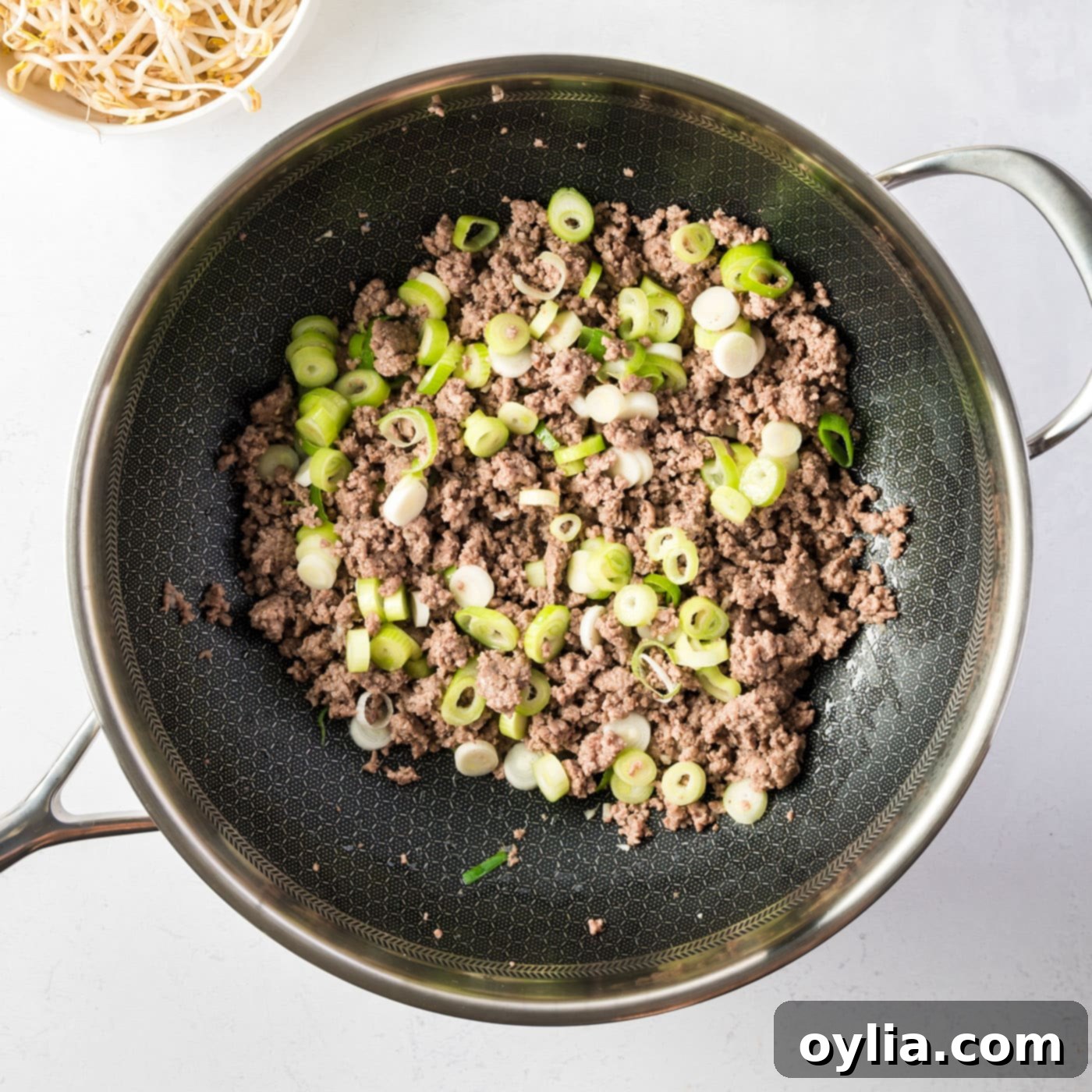 Ground beef, spring onions, and garlic cooking in a skillet