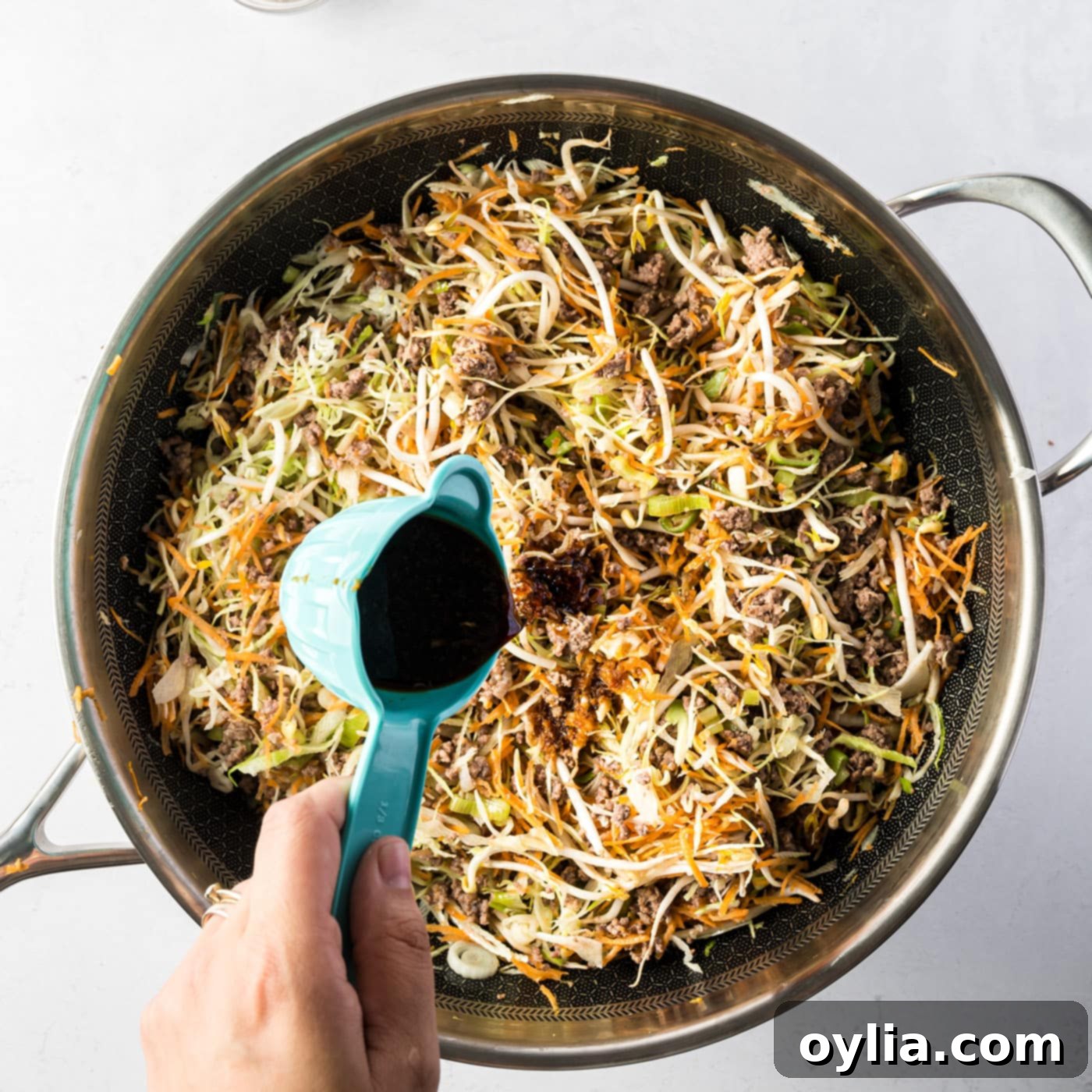 Adding sauce to the egg roll in a bowl mixture