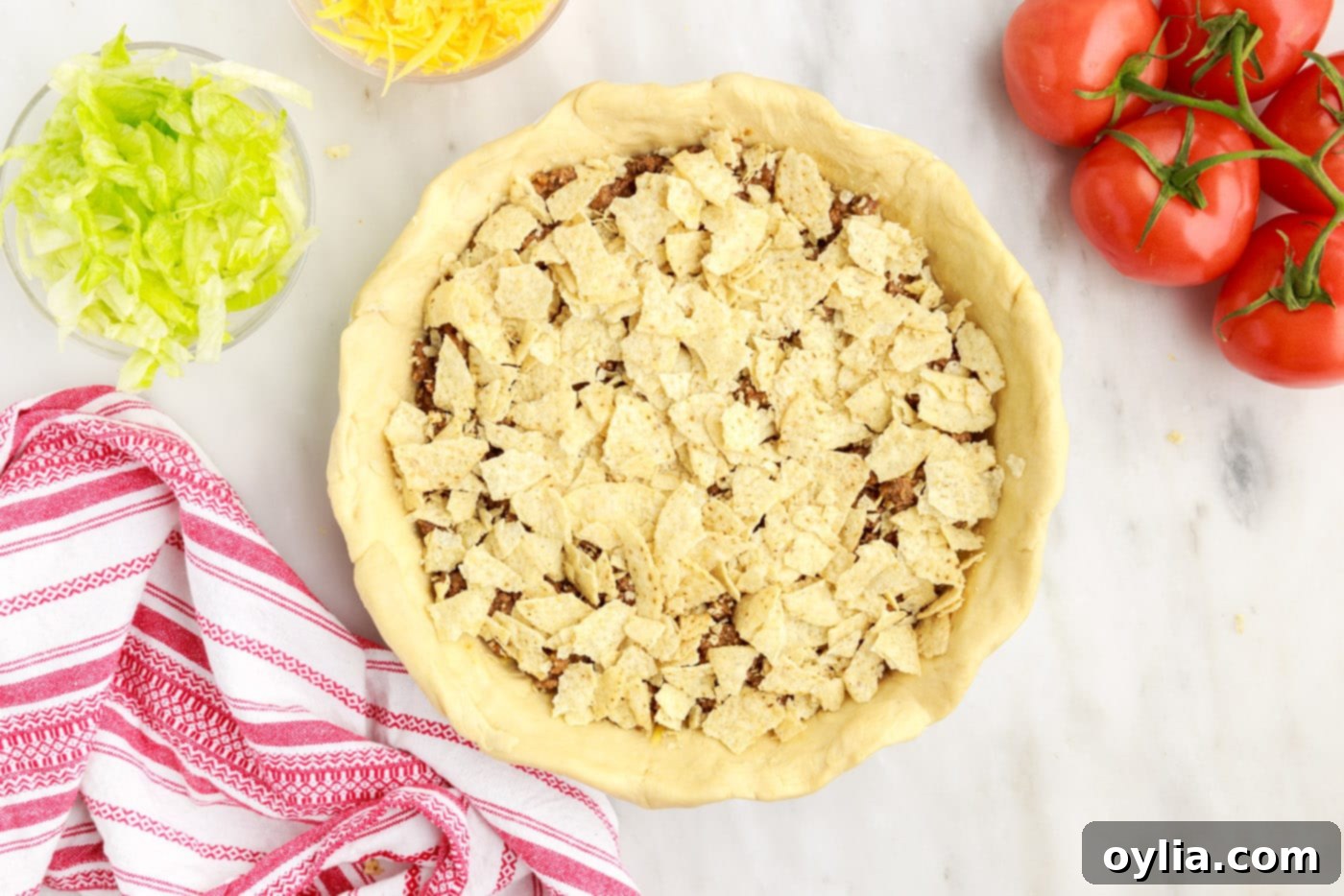 crushed tortilla chips spread over the ground beef layer of the pie