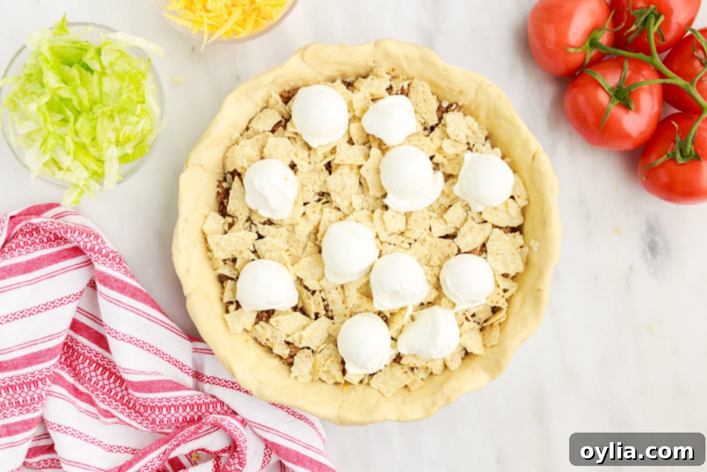 dollops of sour cream spread over the crushed tortilla chips and ground beef layers