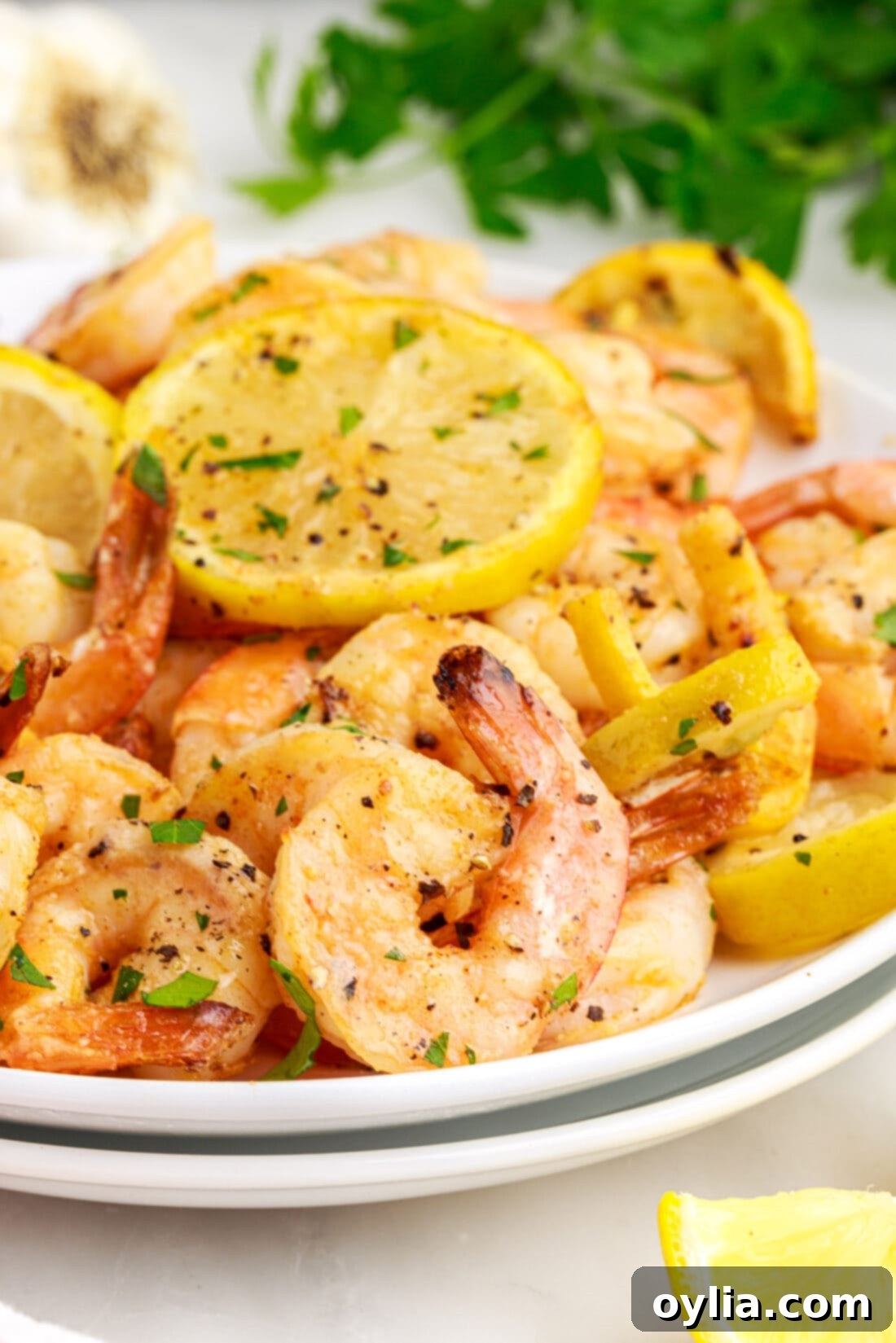 Plate of perfectly cooked Air Fryer Shrimp, garnished with fresh parsley and lemon wedges.