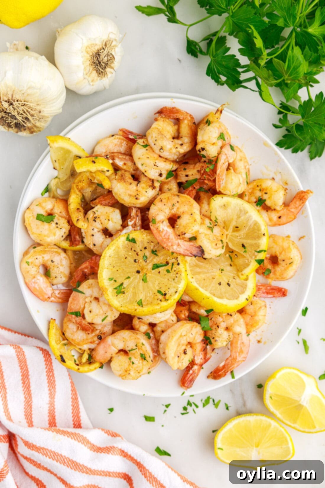 Close-up of a plate of cooked Air Fryer Shrimp, ready to be served, with a sprinkle of fresh parsley.