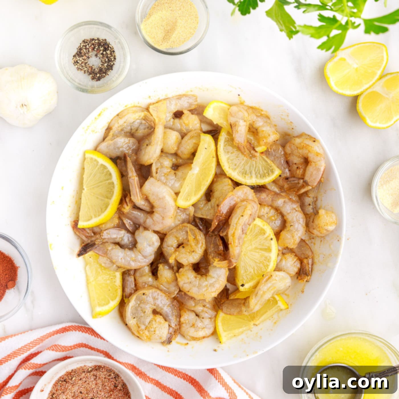 Raw shrimp mixed with lemon wedges in a mixing bowl, prior to air frying.