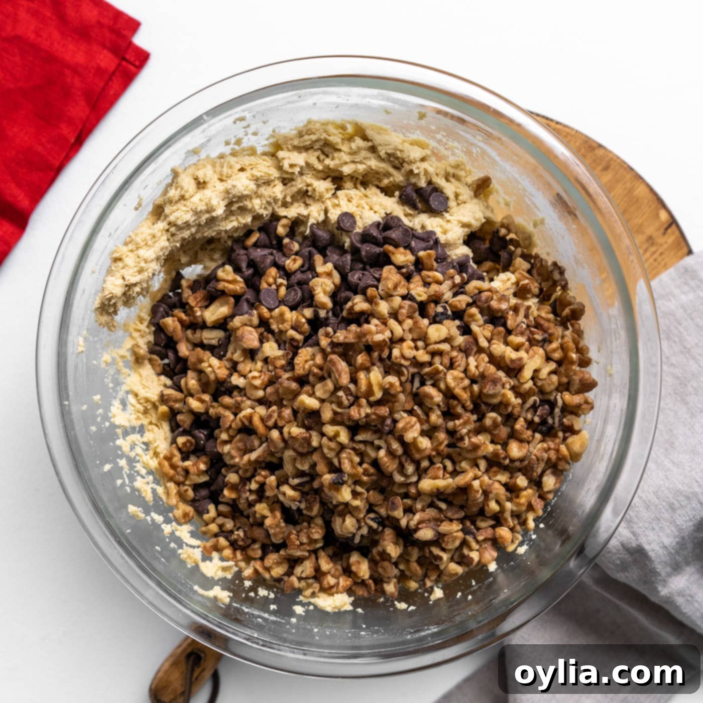 Walnuts and chocolate chips being folded into the Doubletree cookie dough with a wooden spoon