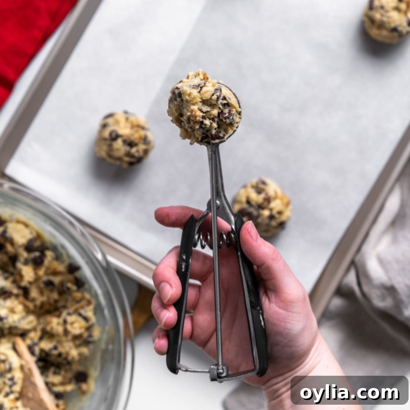 A scoop of Doubletree cookie dough placed on parchment paper on a baking sheet
