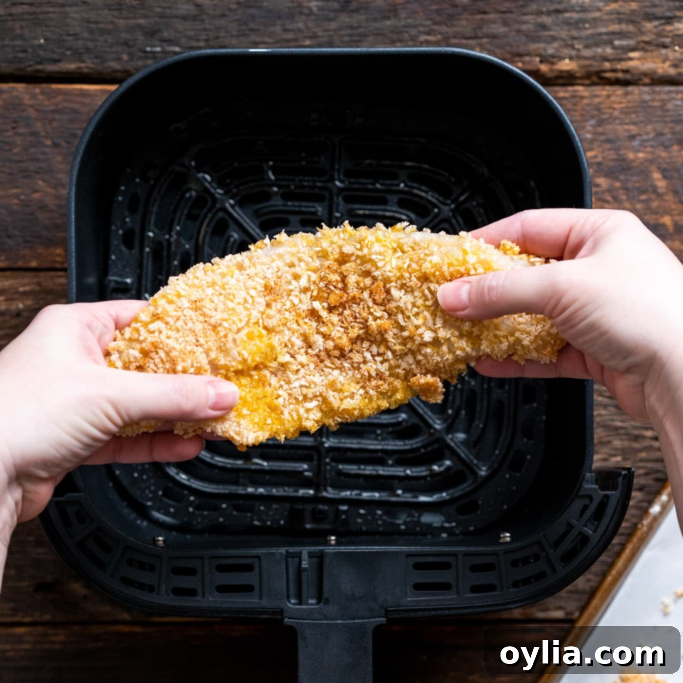 breaded fish above air fryer basket