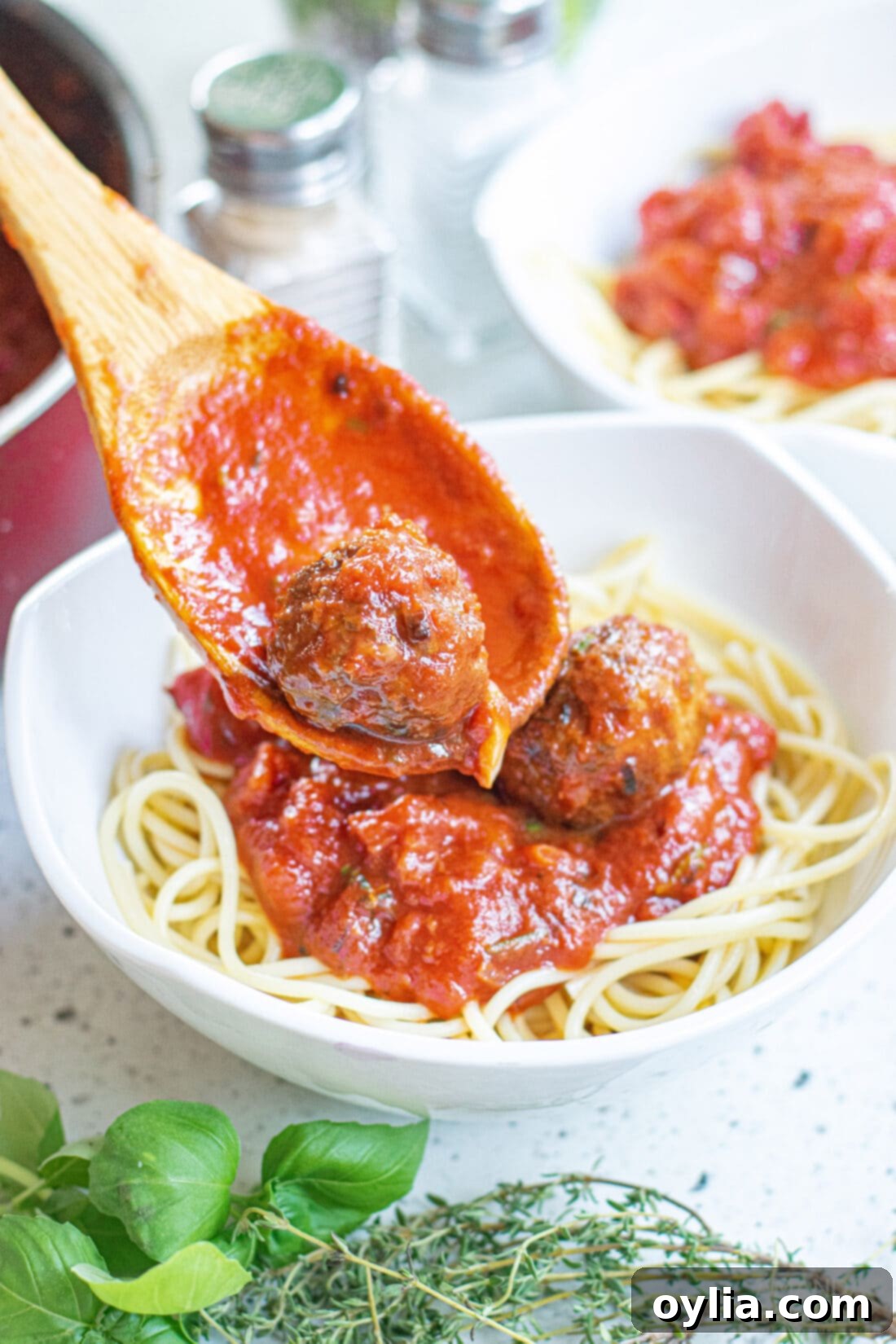 Classic Spaghetti and Meatballs 2 spooning meatballs and marinara over spaghetti noodles