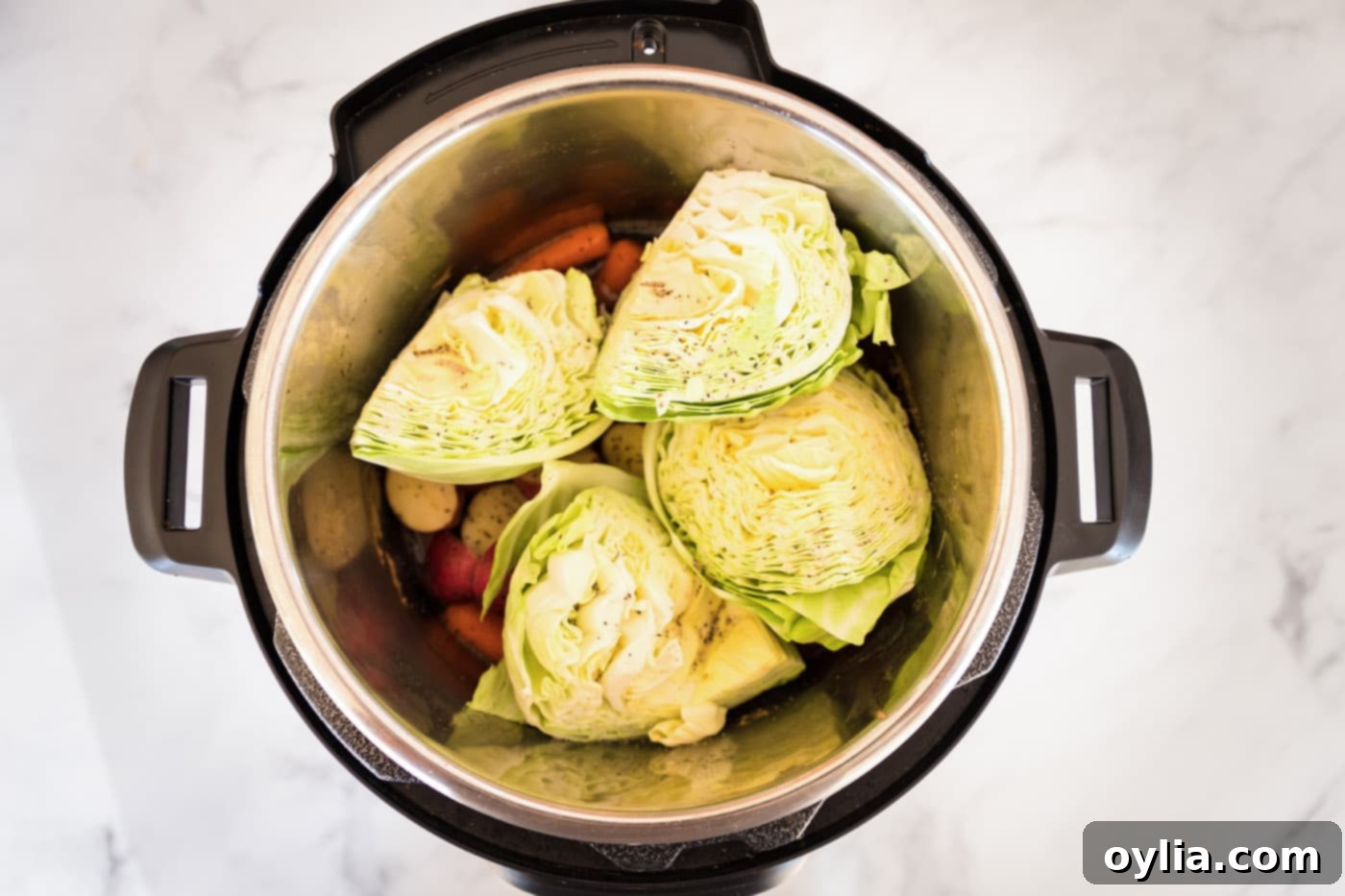 Cabbage wedges layered over baby potatoes and carrots in the Instant Pot