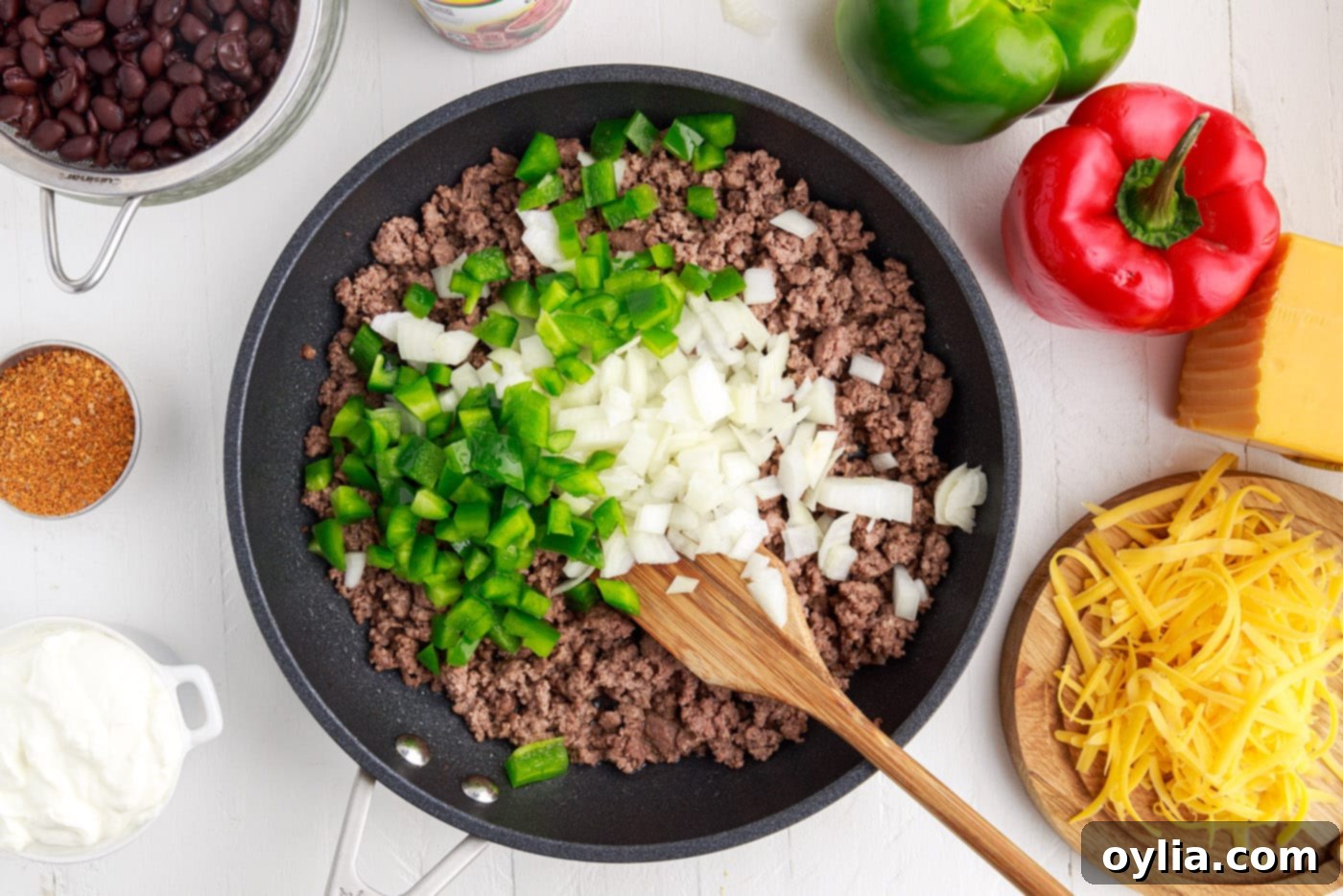 diced onion and bell pepper over ground beef in a pan