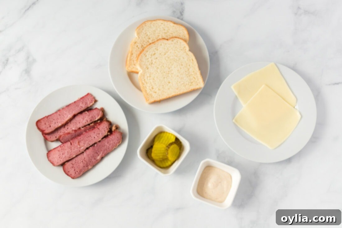 All the fresh ingredients for a corned beef sandwich neatly arranged on a wooden cutting board: sliced corned beef, sourdough bread, mozzarella cheese, dill pickle chips, and a bowl of horseradish mayo.