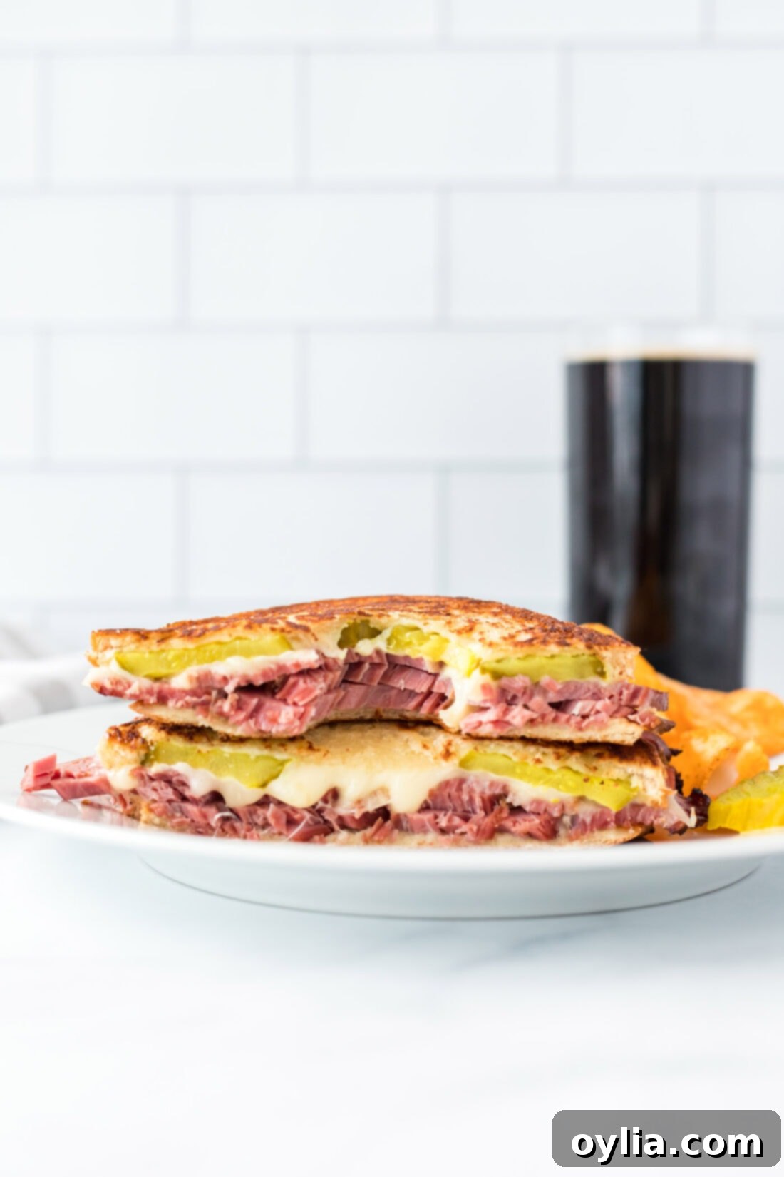 Close-up of a perfectly grilled corned beef sandwich with a bite taken out, clearly showing the tender beef, melted cheese, and crunchy pickle layers.
