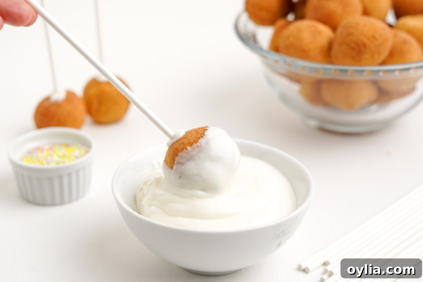 dipping donut hole cake pop into chocolate