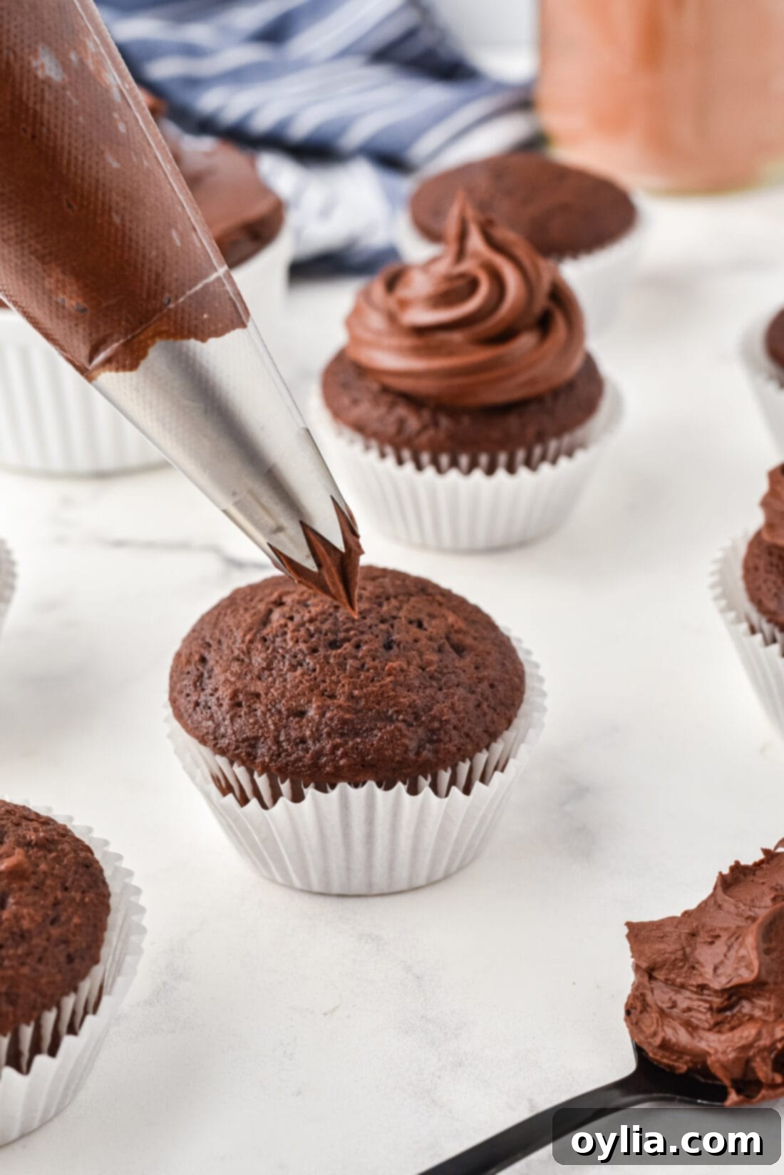 Decadent Chocolate Fudge Frosting 3 Piping Chocolate Fudge Frosting onto a cupcake, showing its beautiful texture.