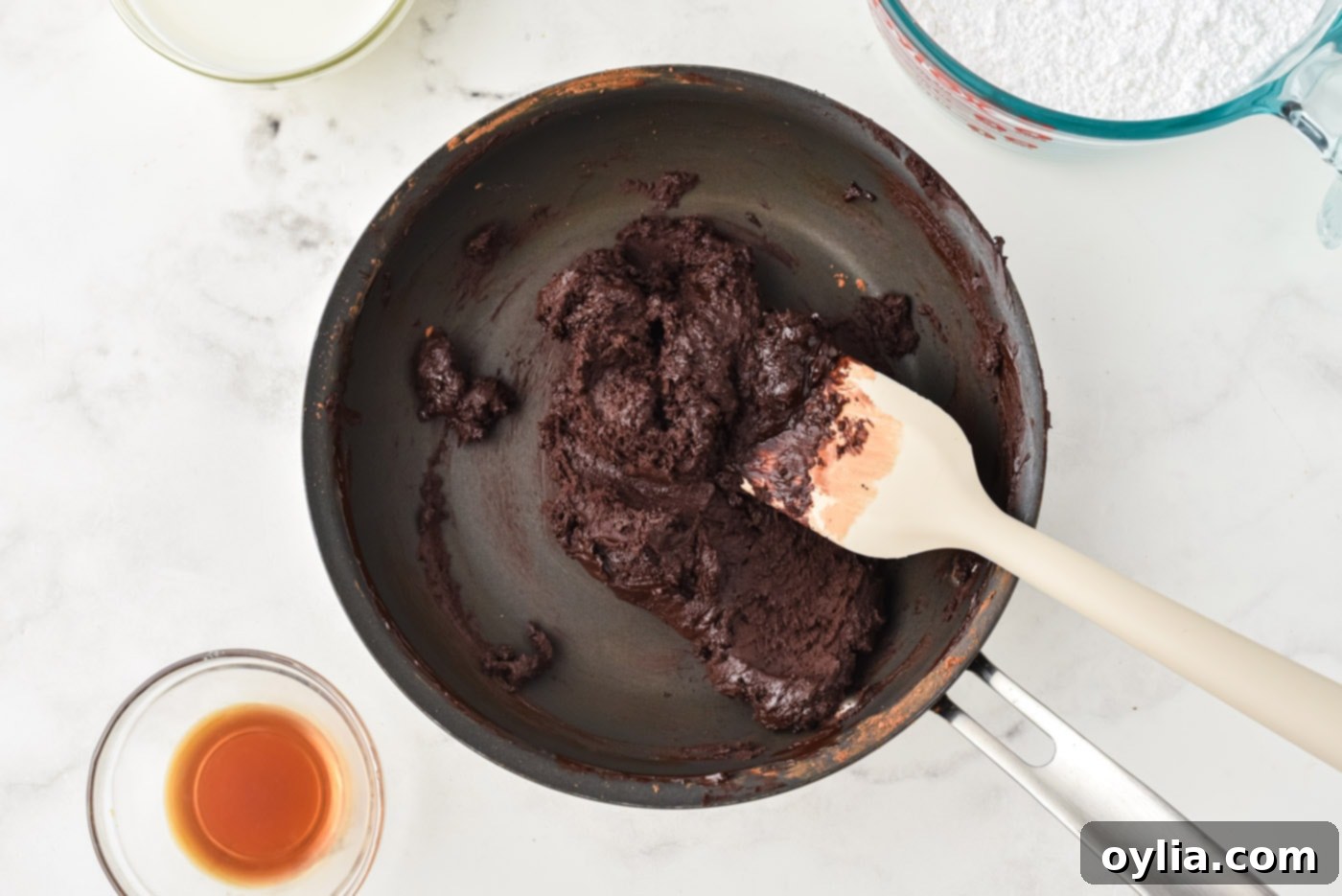 Thick chocolate and butter mixture in a saucepan after cocoa powder is added.