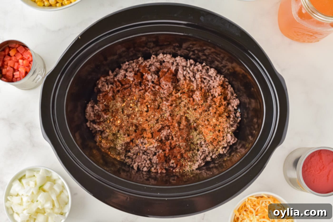 seasonings on top of ground beef in a crockpot
