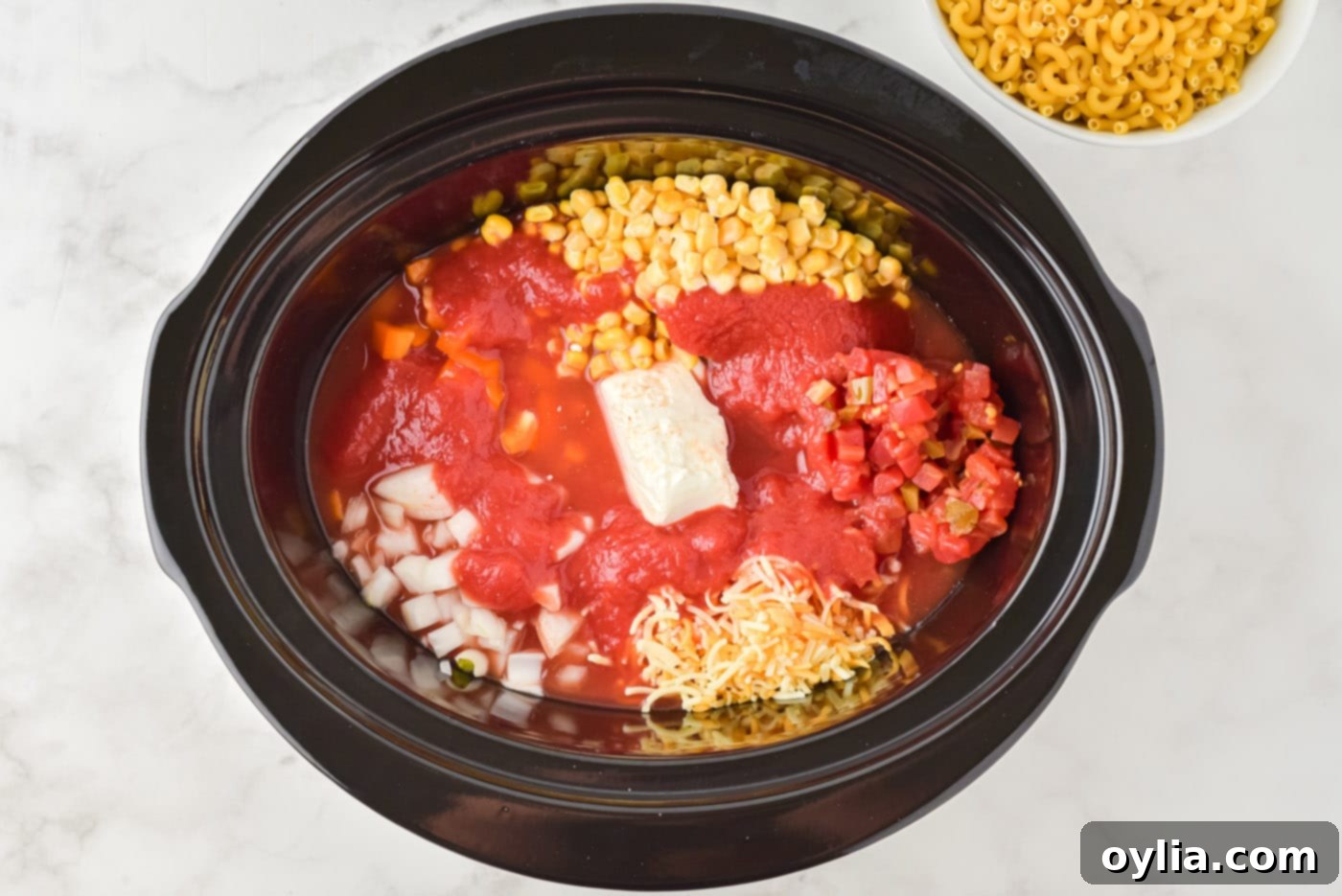 tomato sauce, cream cheese, and veggies in a crockpot layered over ground beef