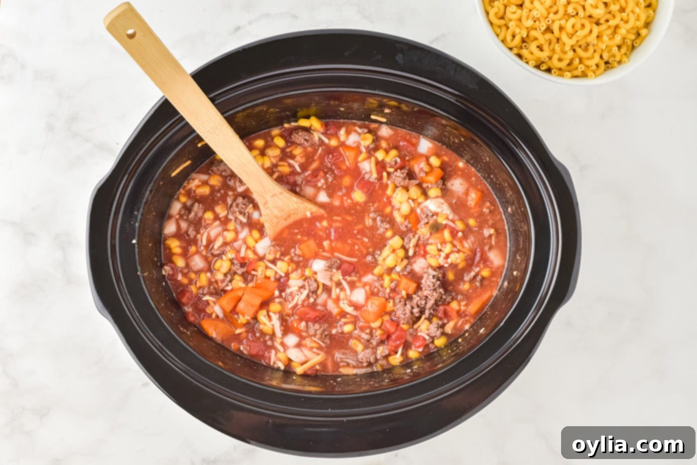 wooden spoon stirring ingredients in a crockpot before slow cooking