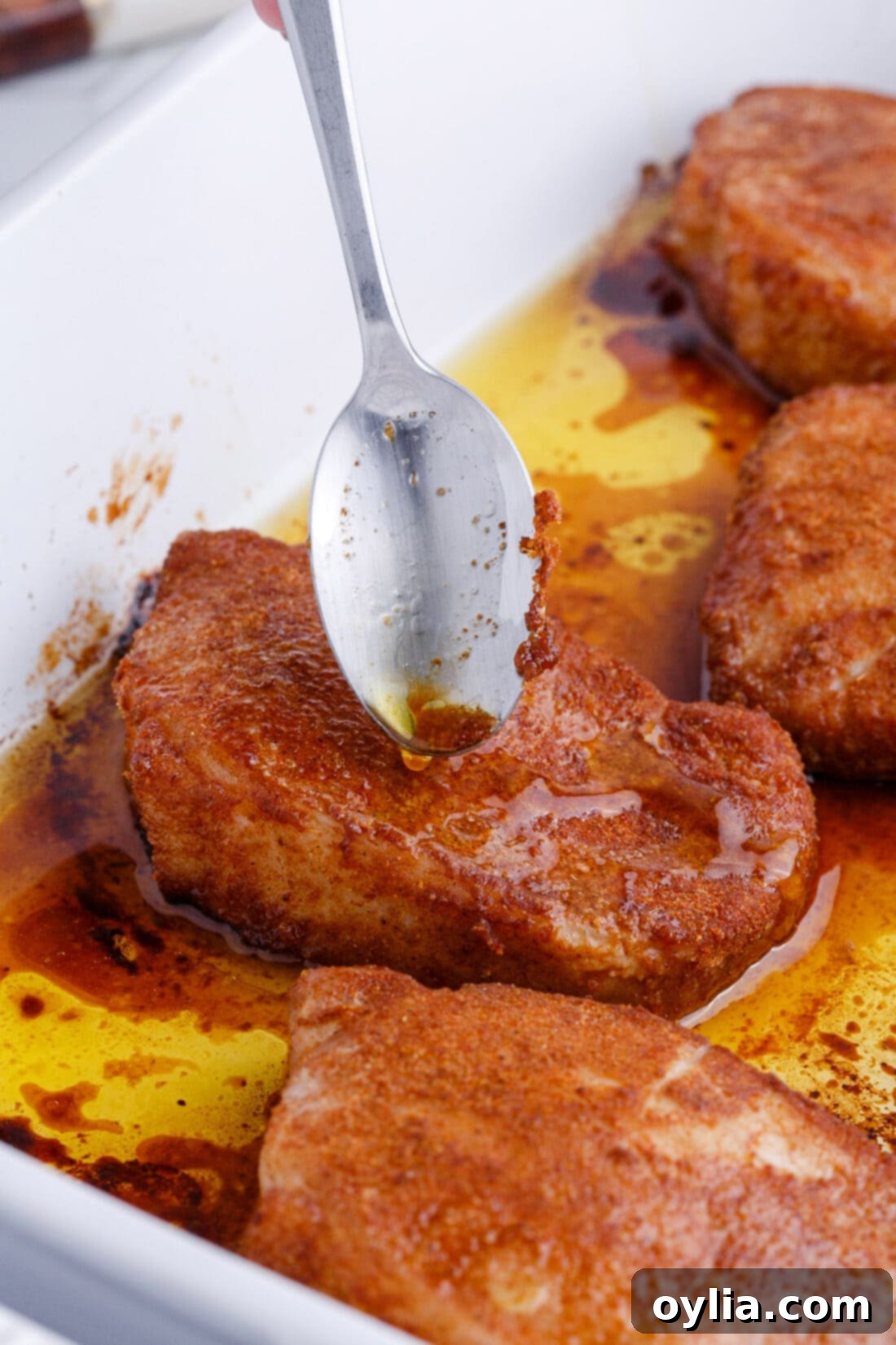 Spoon gently basting juices over freshly baked pork chops