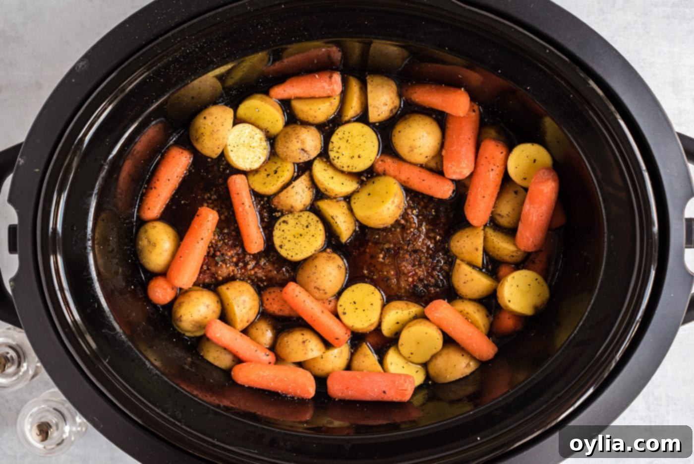 Baby carrots and potatoes added to the crockpot with corned beef
