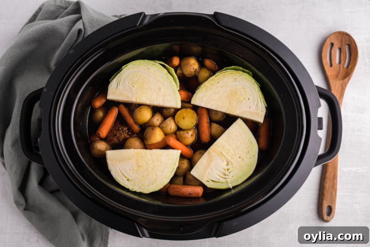Cabbage wedges added to the crockpot with corned beef, carrots, and potatoes