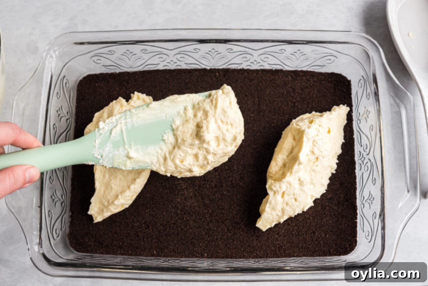 spreading cream cheese mixture on top of oreo crust