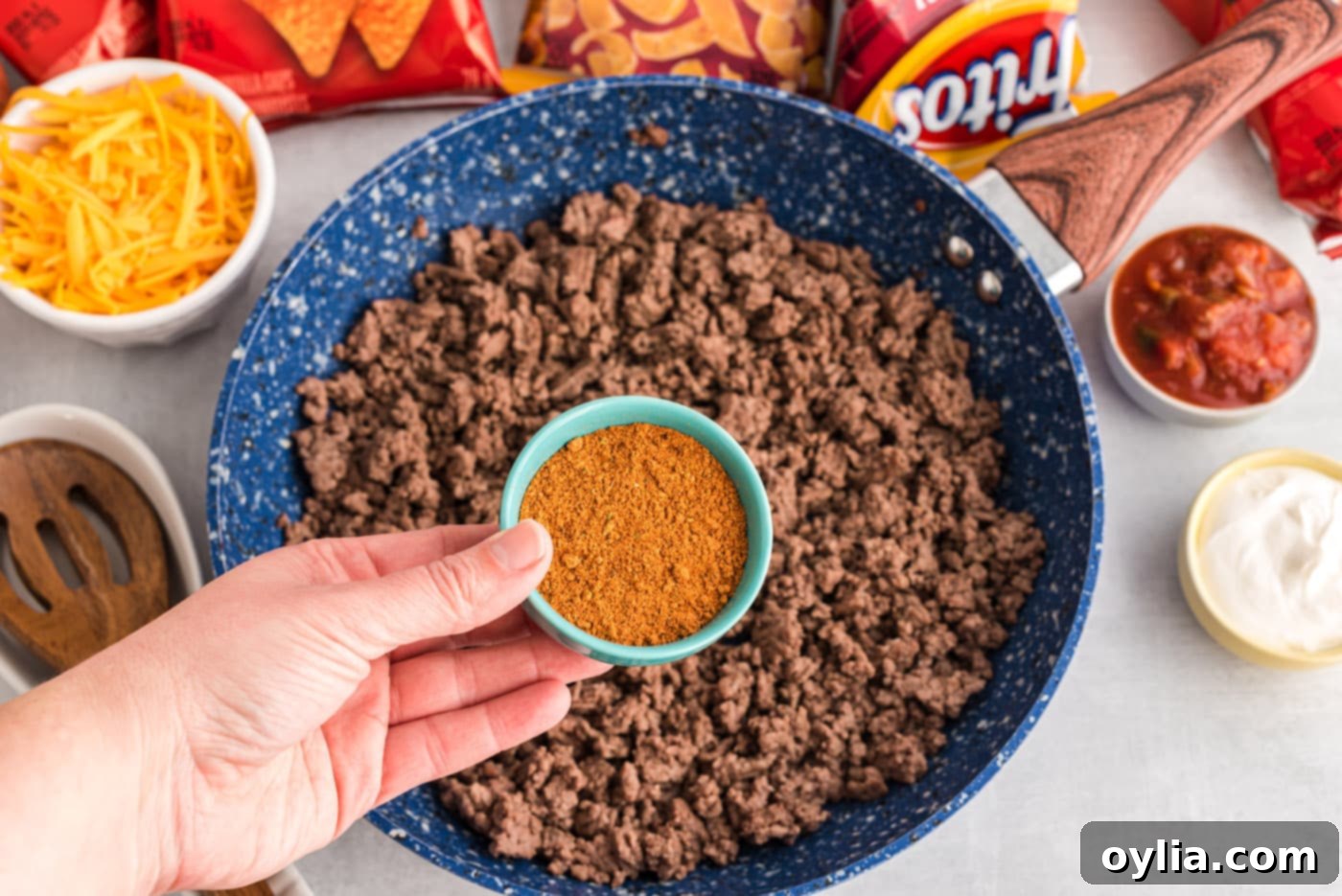 Ground beef cooking in a skillet with taco seasoning and water.