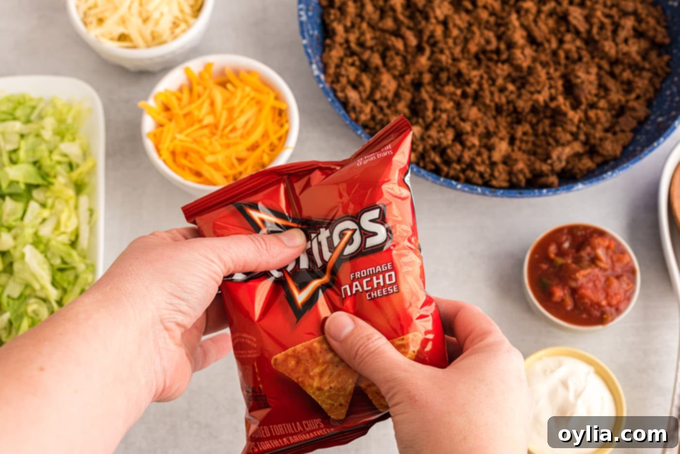 A hand gently crushing a bag of chips for walking tacos.