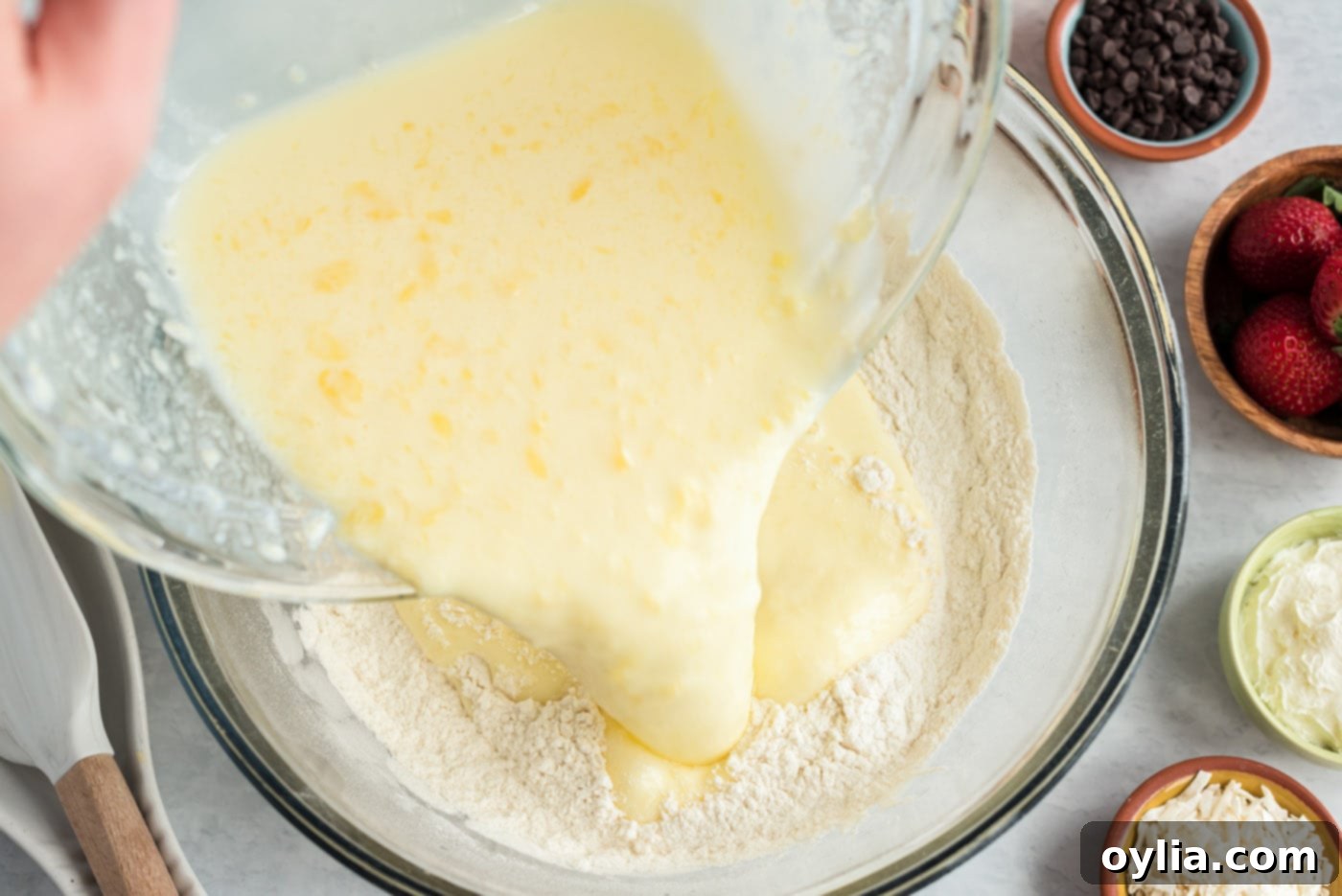 Adding the wet buttermilk mixture to the dry pancake ingredients in a large bowl, ready for mixing.