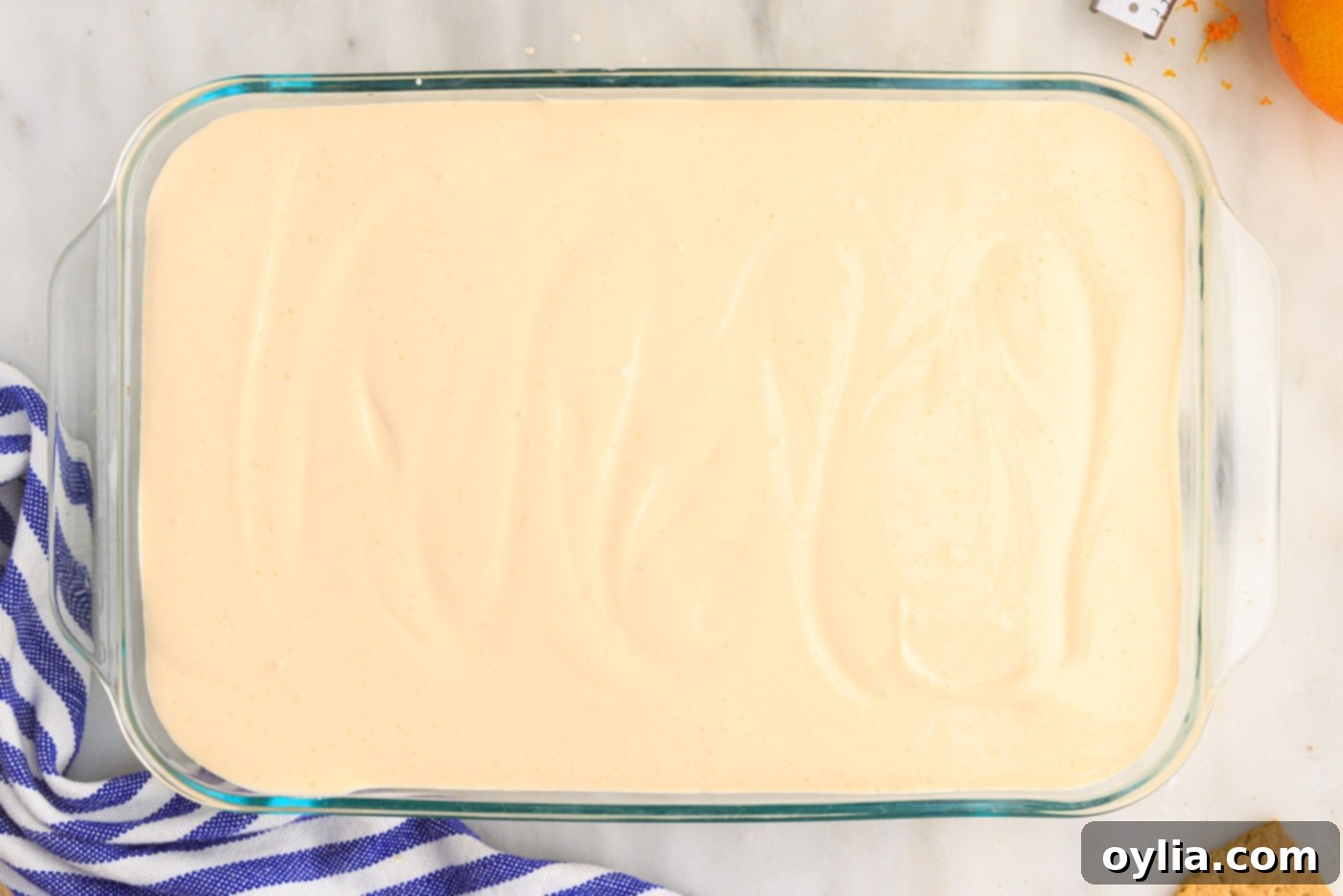 orange pudding mixture over graham crackers in a casserole dish