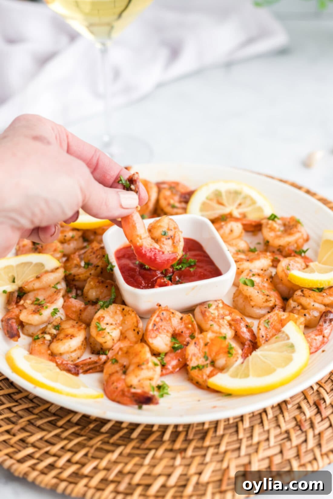 close up of a hand dipping sauteed shrimp in cocktail sauce
