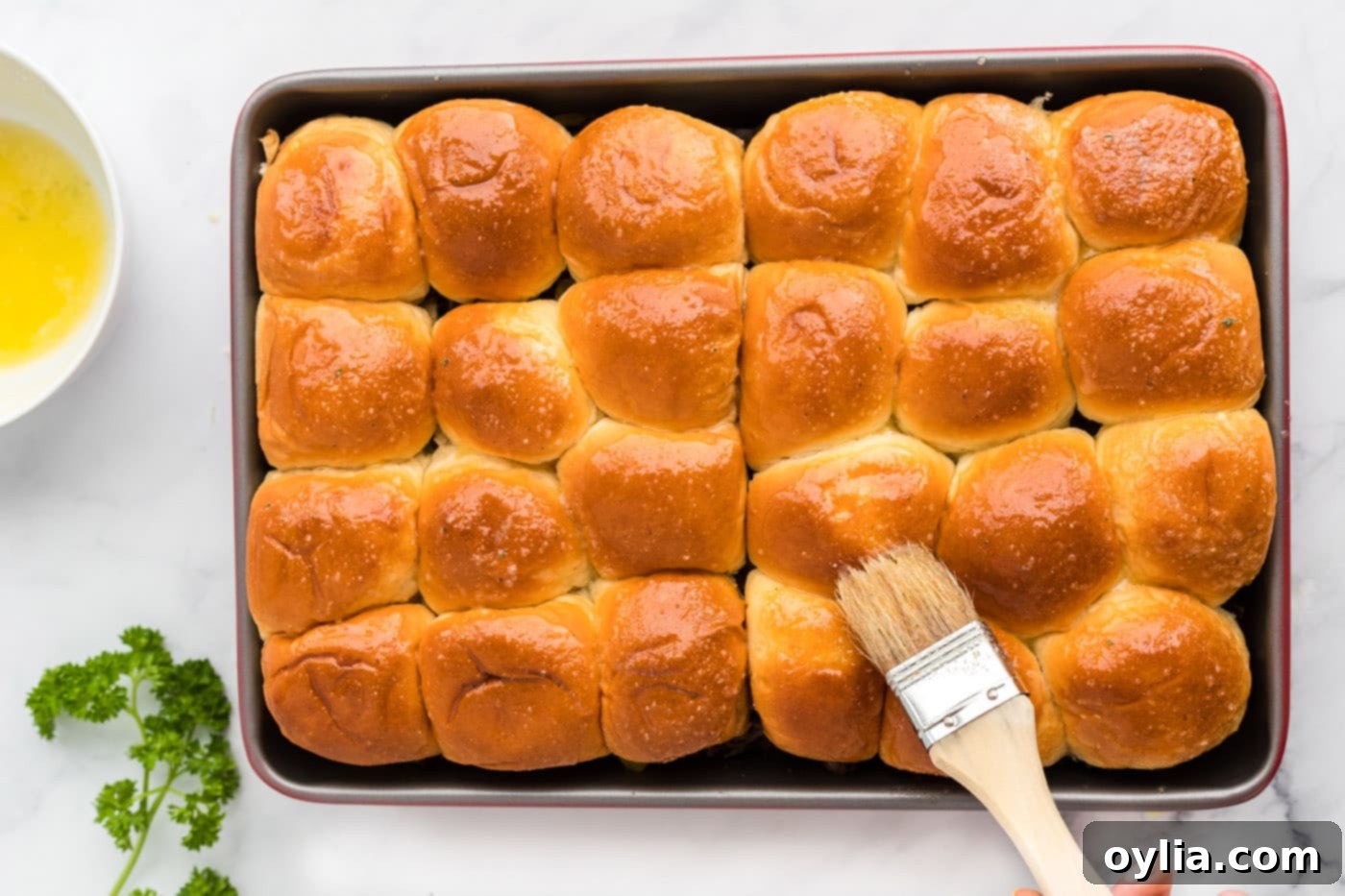 brushing on garlic butter on top of mississippi pot roast sliders