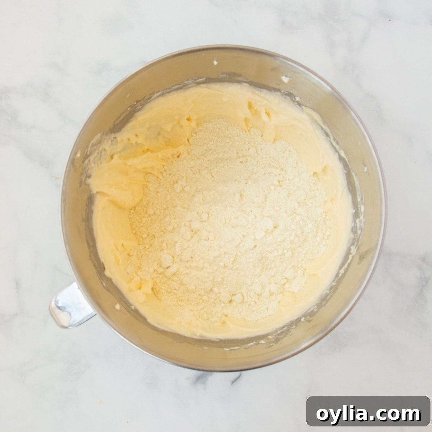 Dry lemon cake mix being mixed into the creamy lemon cookie dough