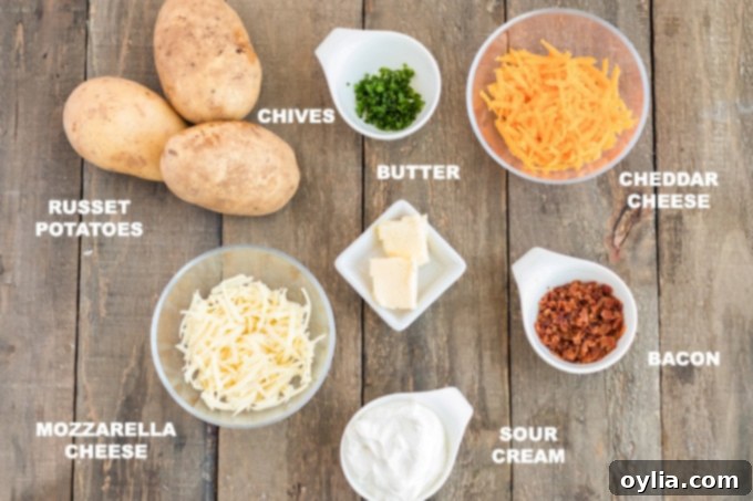 Cheesy Bacon & Chive Twice Baked Potatoes Assortment of fresh ingredients laid out on a table, including russet potatoes, various cheeses, butter, sour cream, bacon, and chives, ready for twice baked potato preparation.