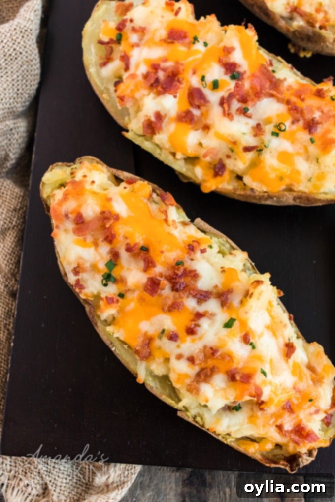 These twice baked potatoes were surprisingly easy to make! Packed with cheese, bacon, and chives, these stuffed potatoes are a favorite in this house. Overhead view of several golden-brown twice baked potatoes garnished with fresh chives, presented on a baking sheet, ready to be enjoyed.