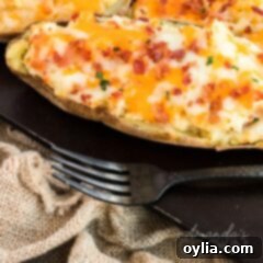 Double-Baked Potato Perfection 5 A single perfectly baked and stuffed twice baked potato sitting on a rustic metal pan, ready to be served.