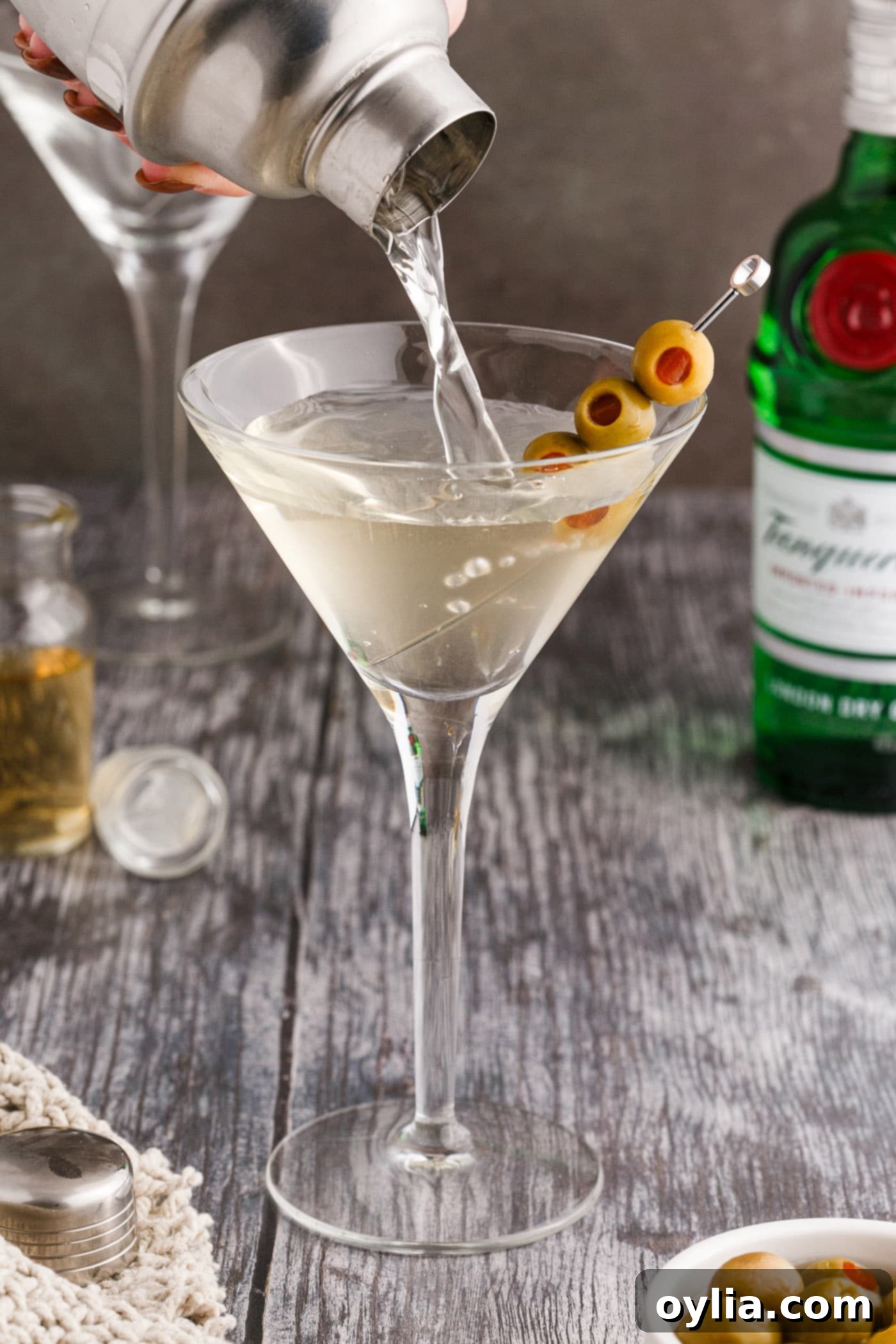straining dirty martini into martini glass