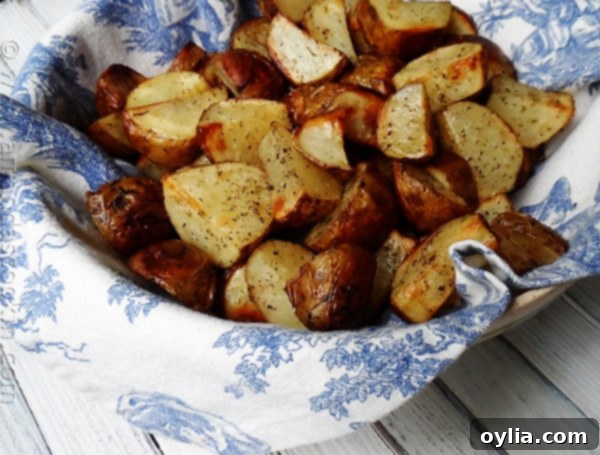 A close-up of beautifully cut and roasted golden-brown potatoes, with crispy edges and tender insides, garnished with fresh herbs, ready to be served.